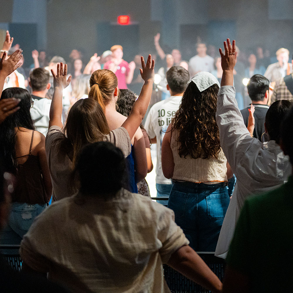 Young adults worshipping together with hands raised