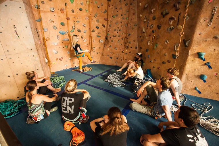Members sitting together at the base of a climbing wall